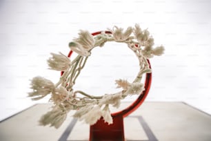 a wreath of white flowers on a red stand