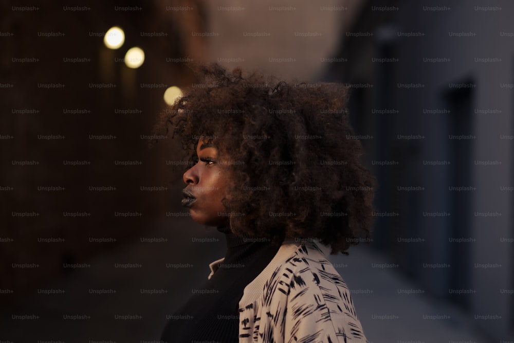 a woman with curly hair standing on a sidewalk