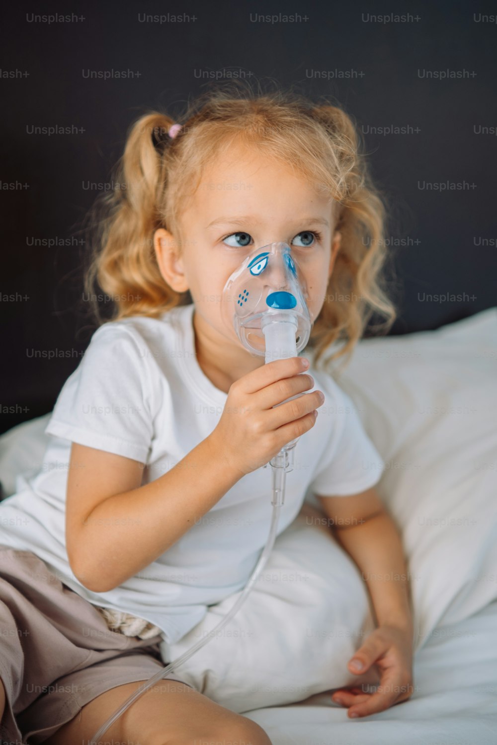 a little girl sitting on a bed with a pacifier in her mouth