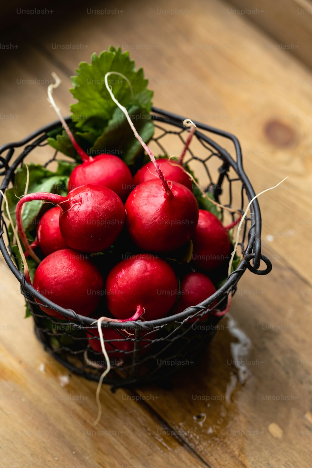 a basket filled with red radishes on top of a wooden table
