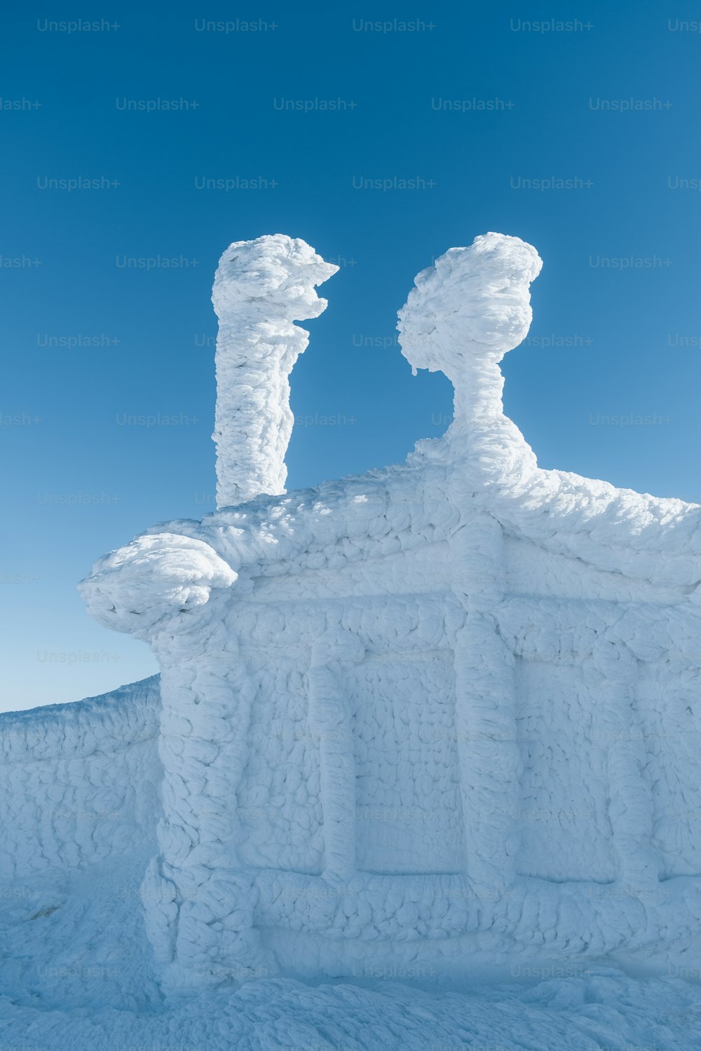 a building made out of snow with a blue sky in the background