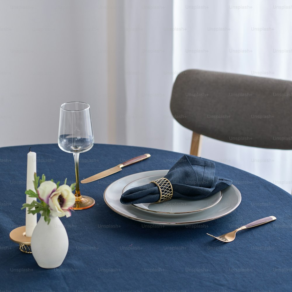 ein Tisch mit blauer Tischdecke und einer weißen Vase mit Blumen