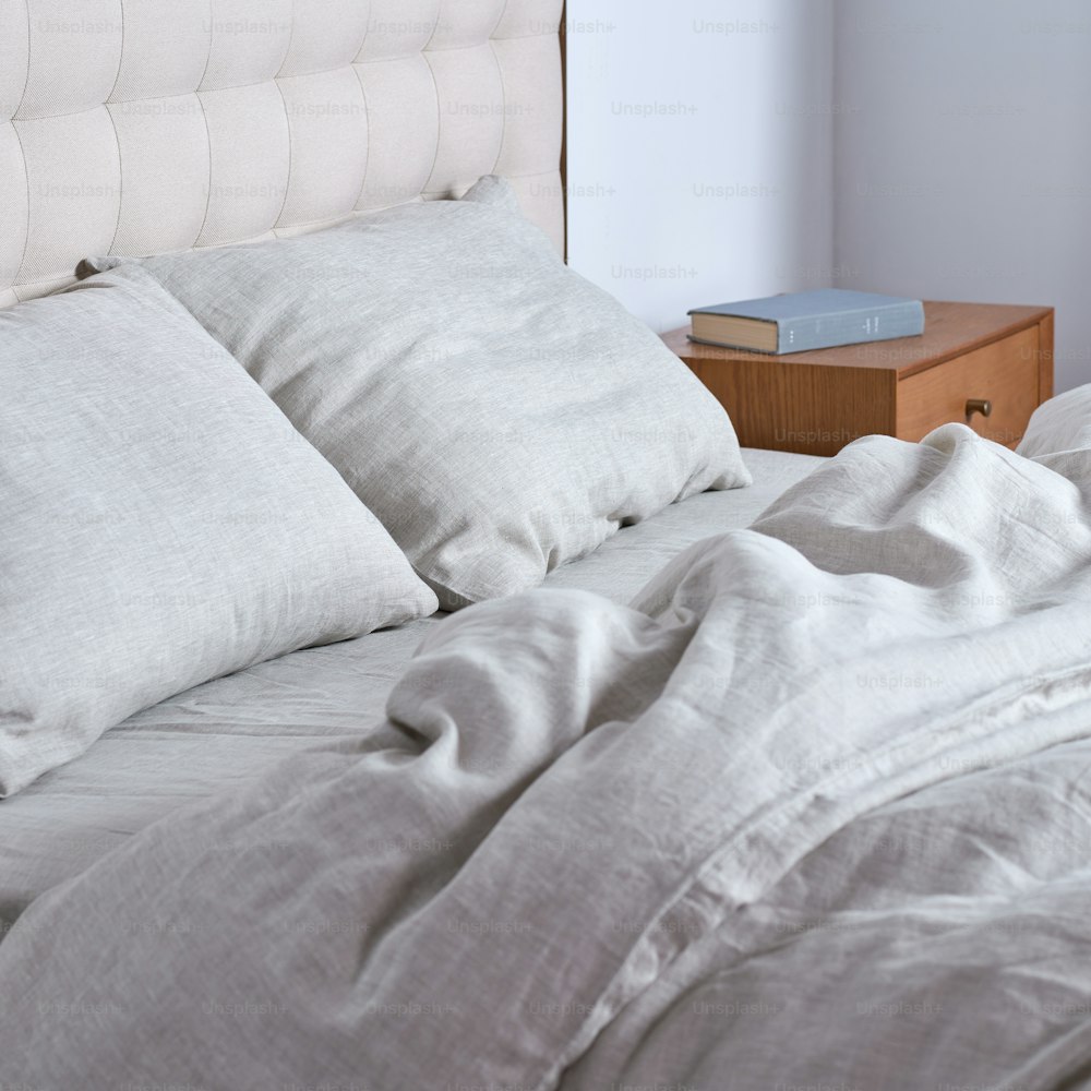 uma cama com um edredom branco e almofadas