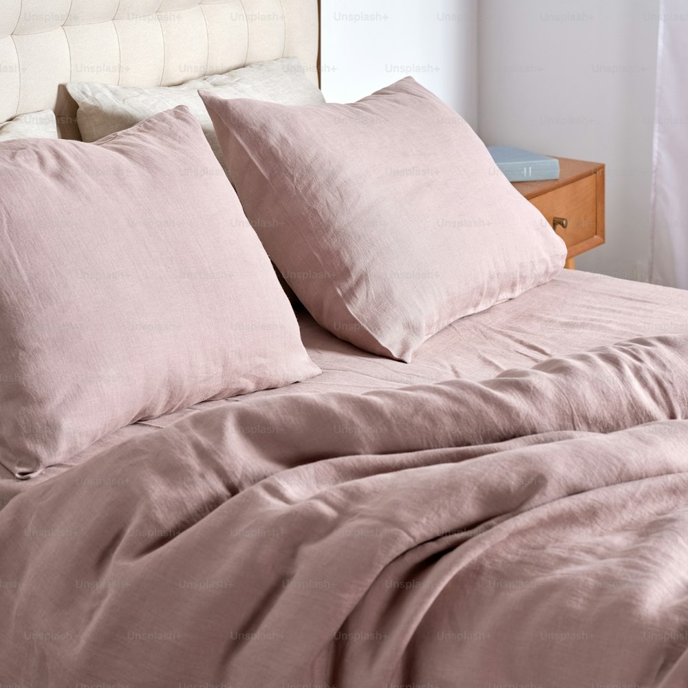 a bed with a pink comforter and pillows