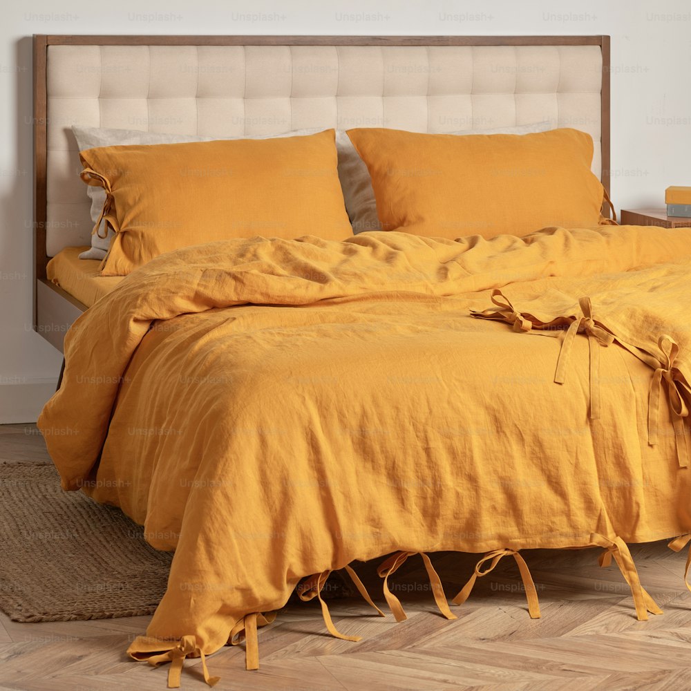 a bed with a yellow comforter and pillows