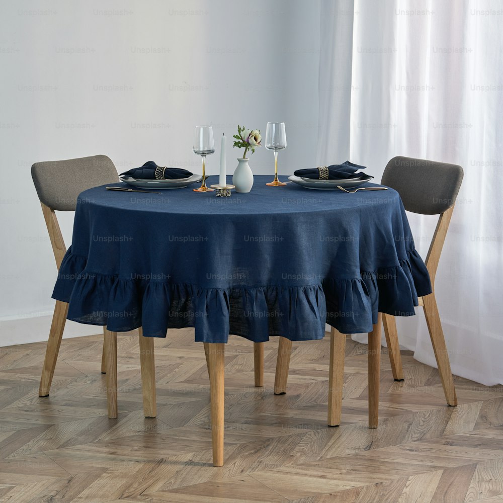 a table with a blue tablecloth and two chairs