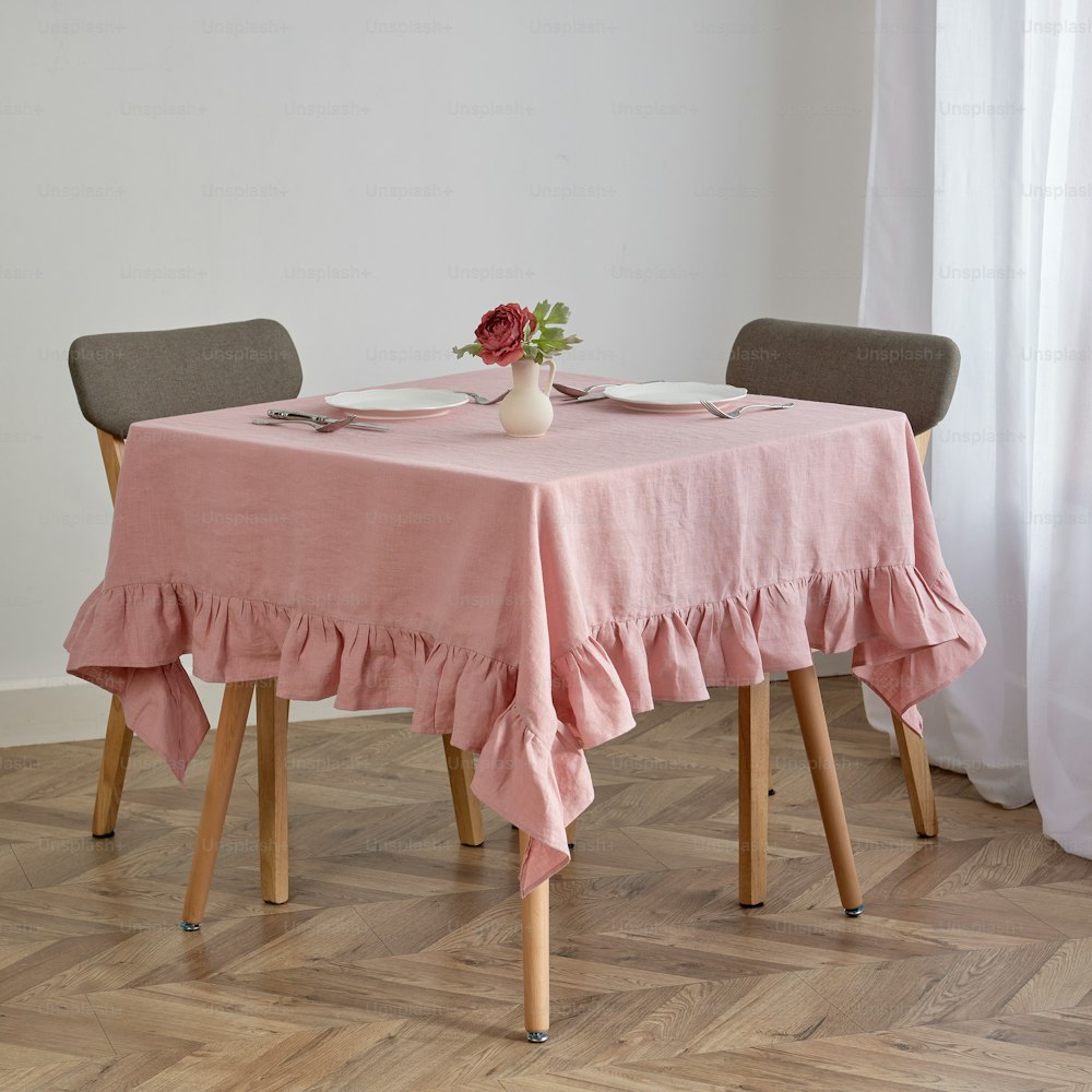a table with a pink table cloth and a vase of flowers