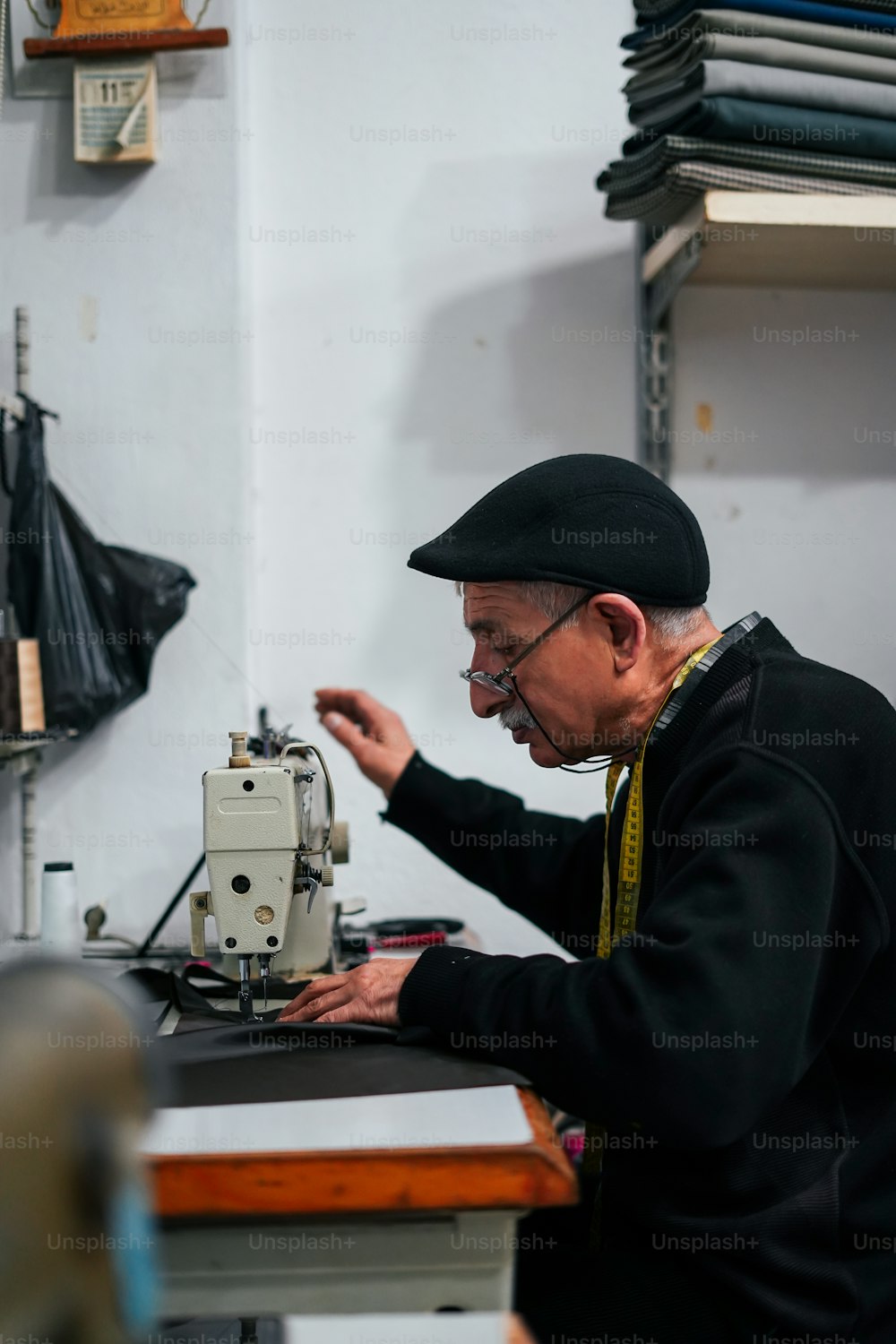 Un vieil homme travaille sur une machine à coudre