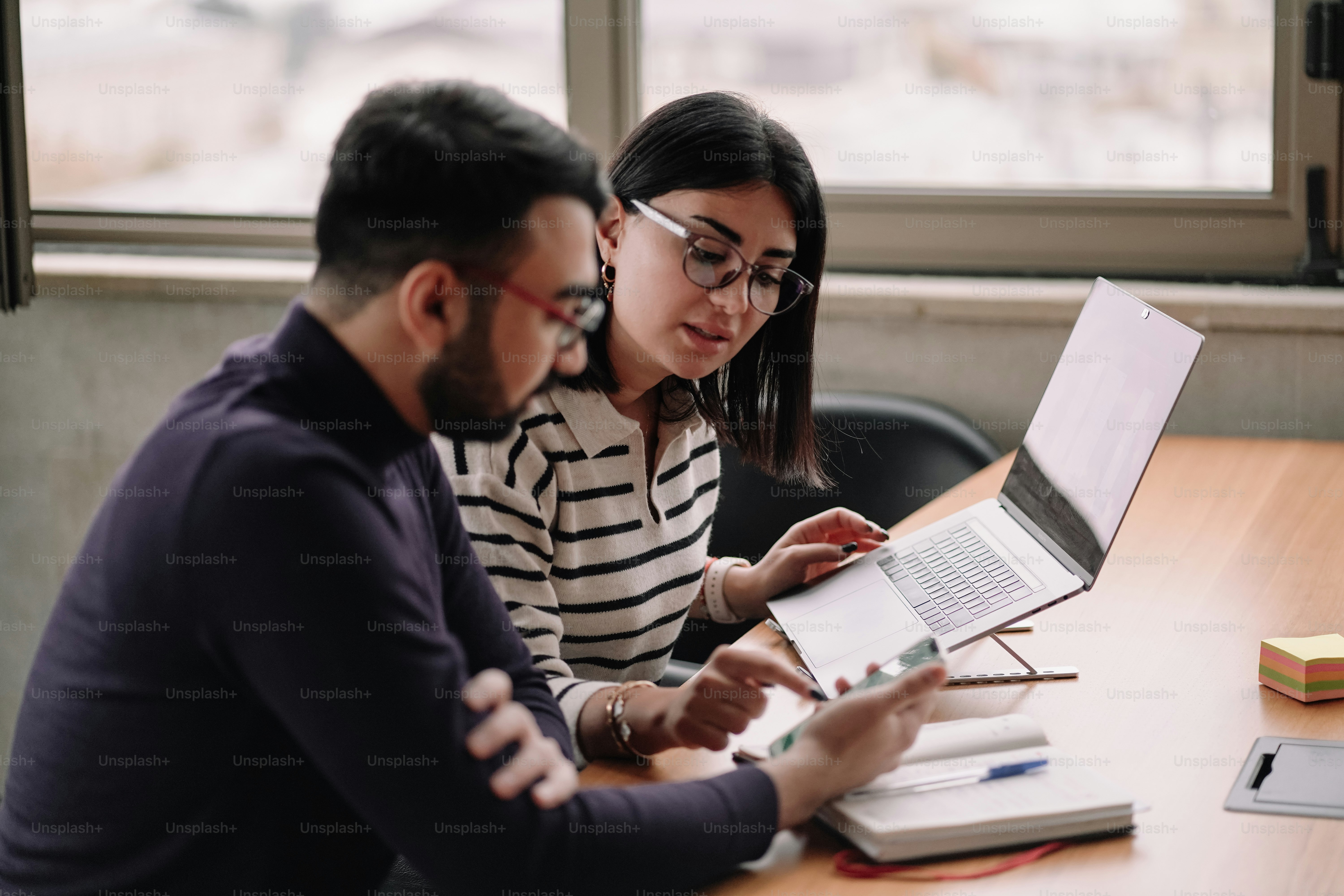 two people sitting at a table looking at a laptop