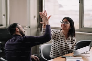 a man and a woman sitting at a table high fiving