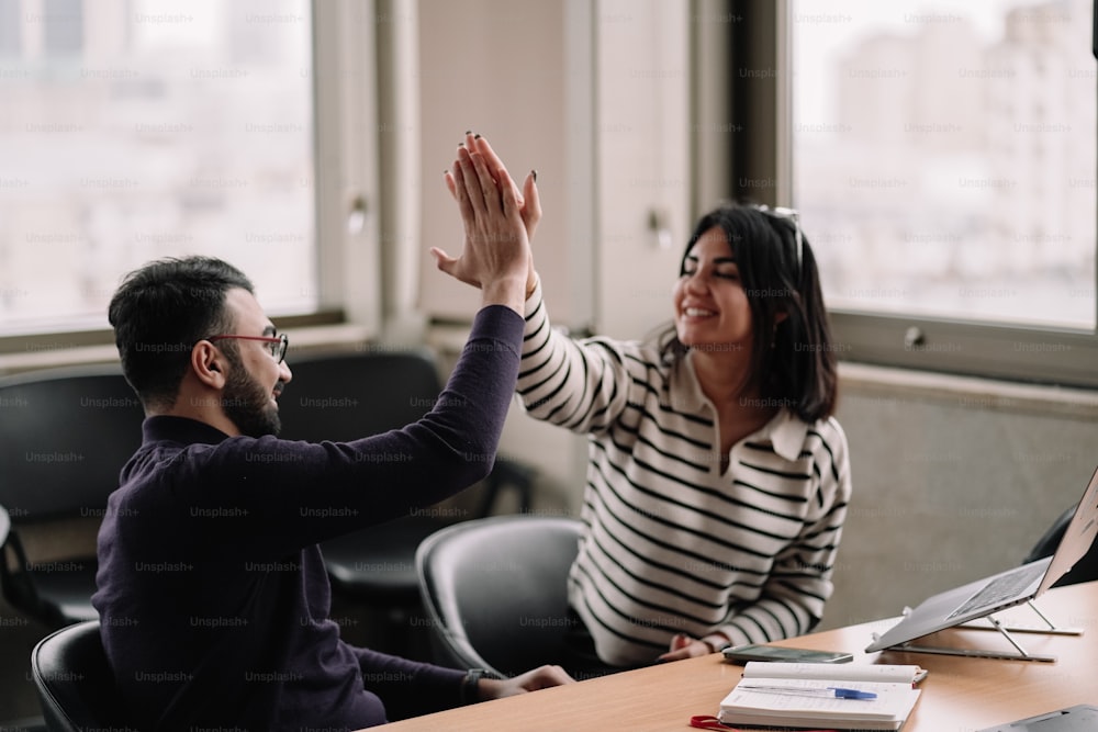 uma mulher dando um high five a um homem em um escritório