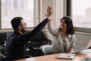 a woman giving a high five to a man in an office