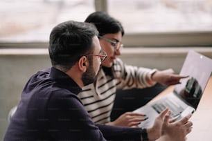 a couple of people sitting at a table with a laptop