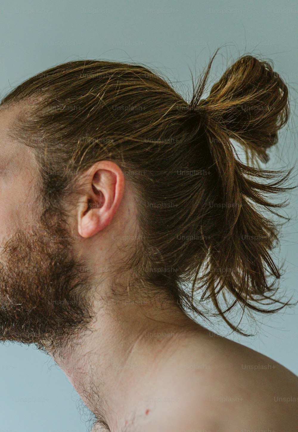 a man with a messy top knot on his hair