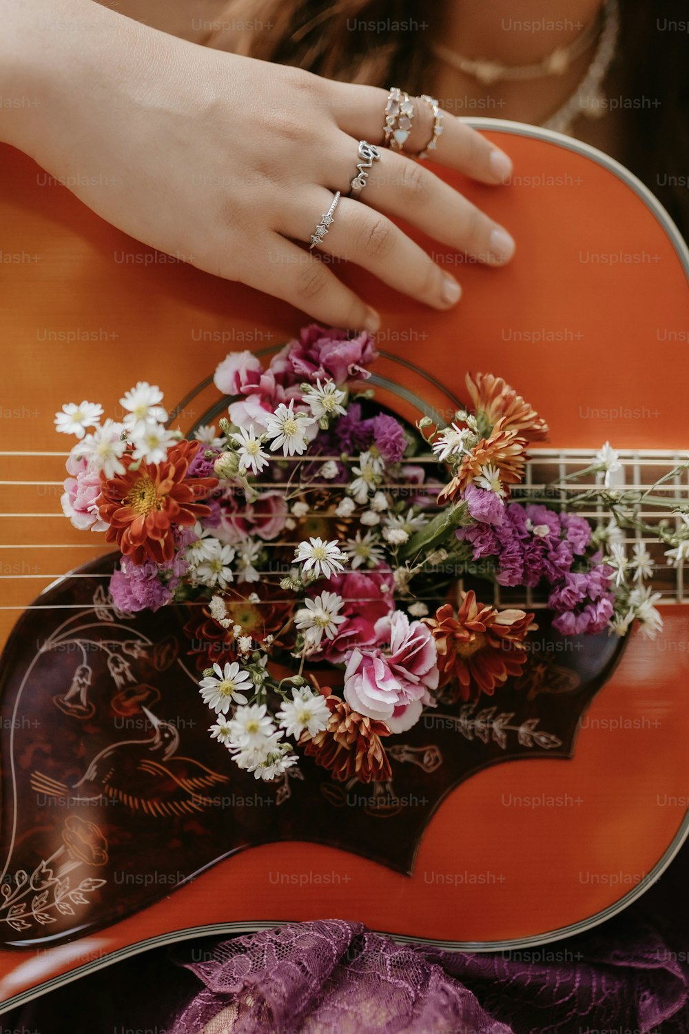 uma pessoa segurando um violão com flores sobre ele