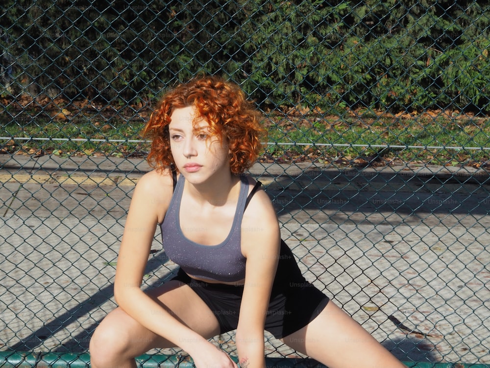 a woman with red hair sitting on a tennis court