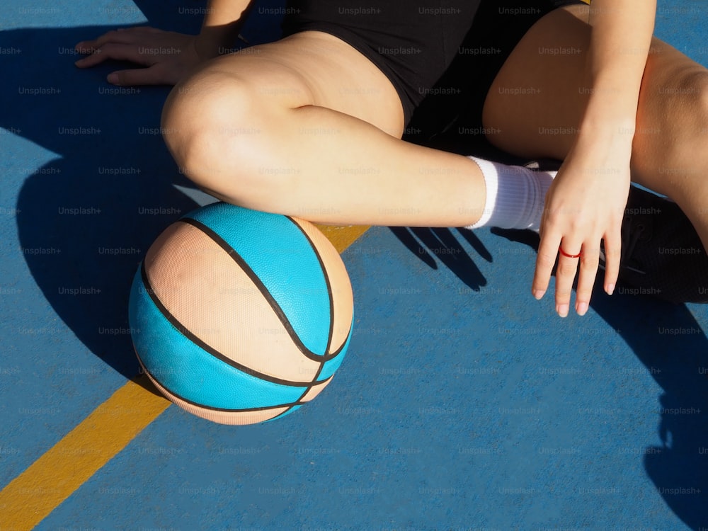 uma mulher sentada no chão com uma bola de basquete