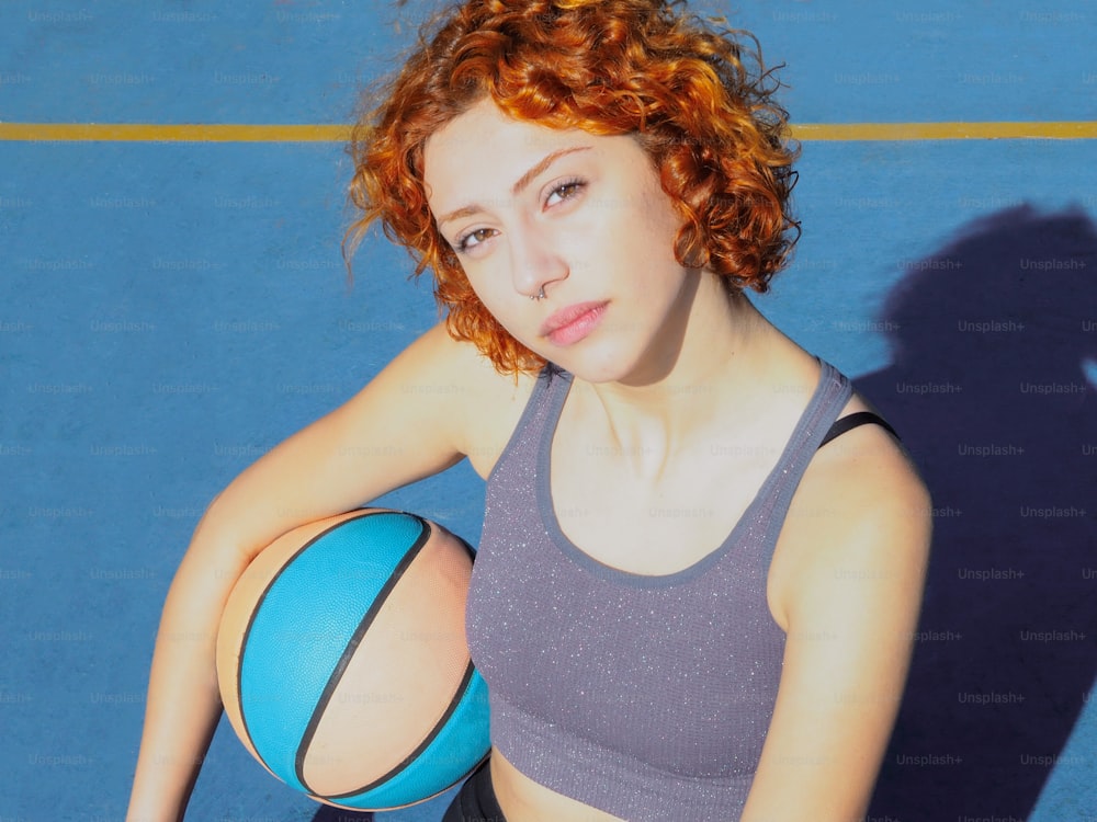 a woman with red hair is holding a basketball