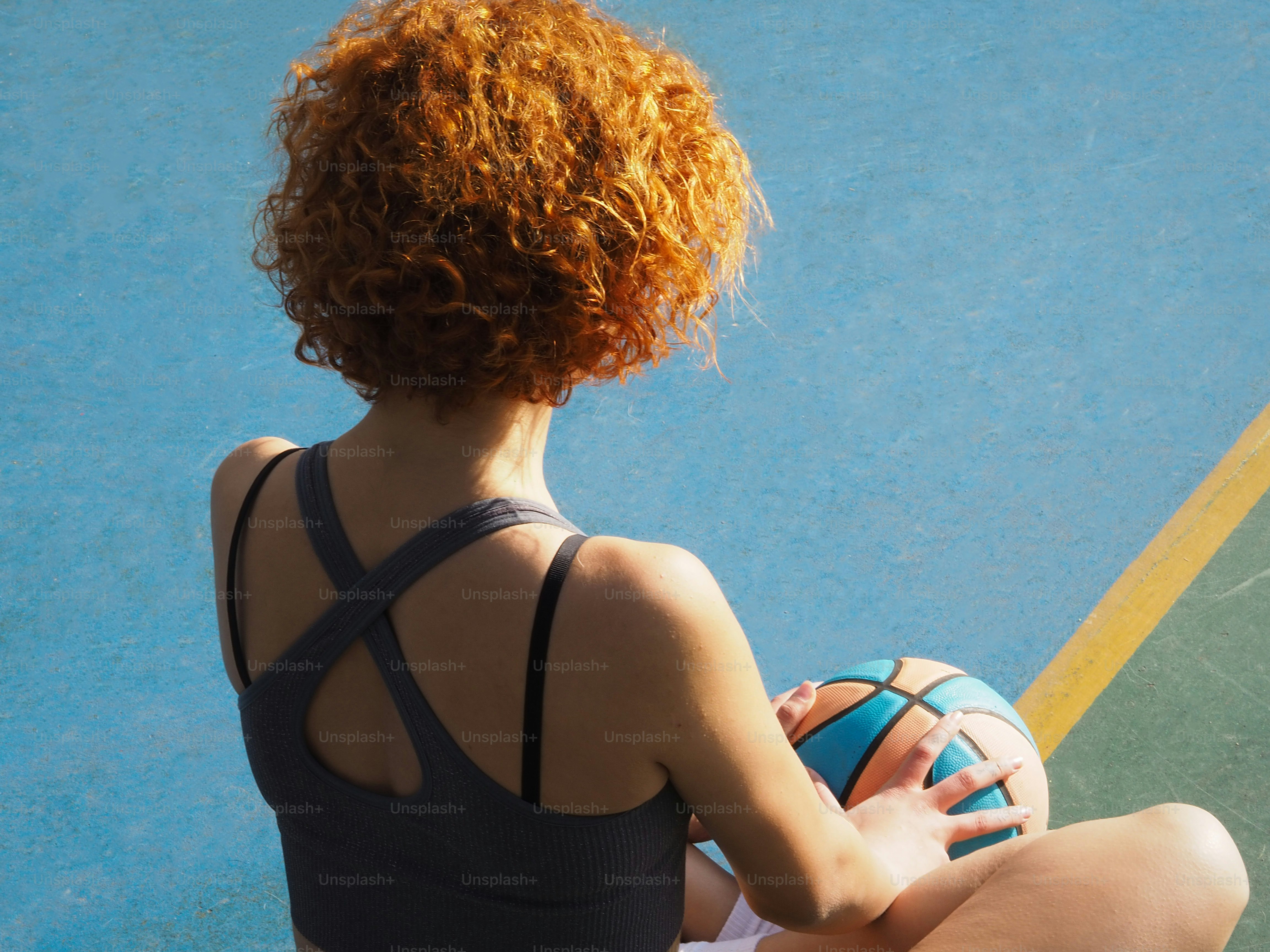 a woman sitting on a tennis court holding a ball