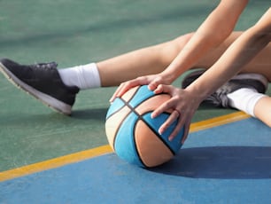 a close up of a person holding a basketball on a court