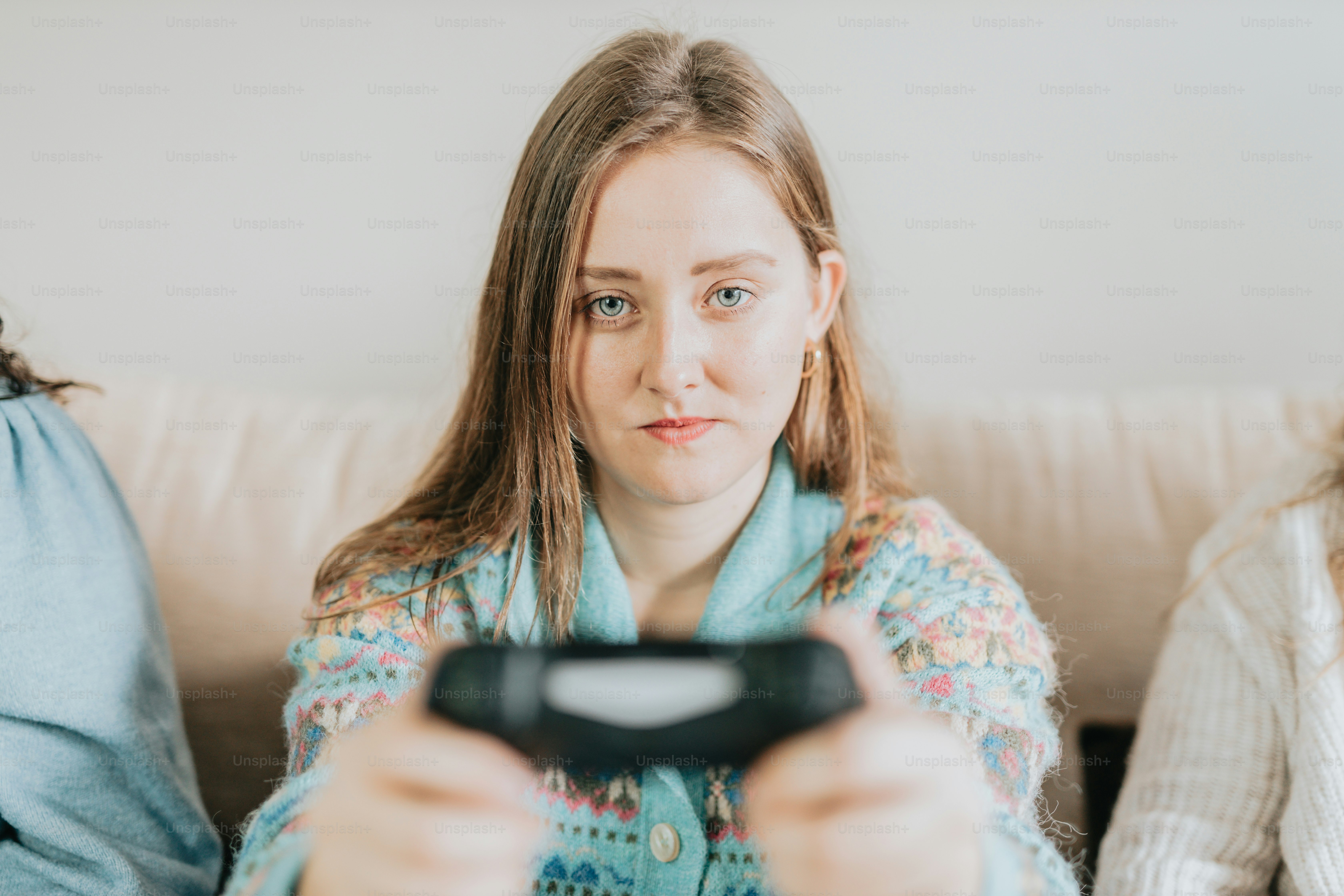 Eine Frau sitzt auf einer Couch und hält eine Fernbedienung in der Hand