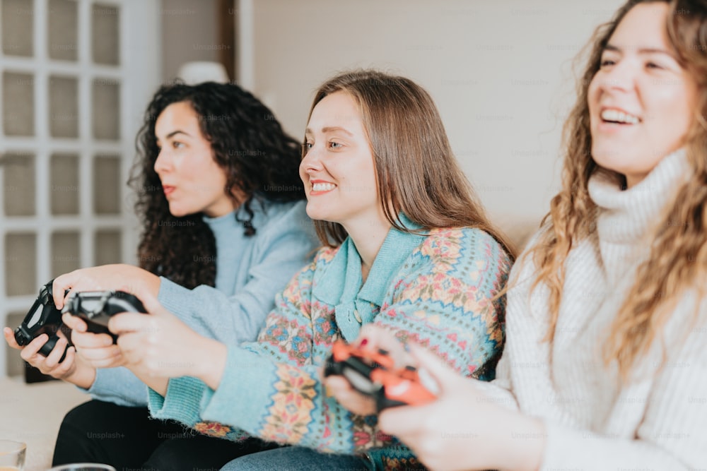 three women sitting on a couch playing a video game
