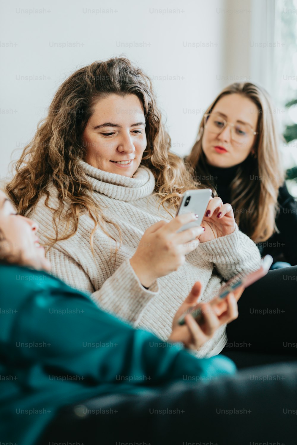 two women sitting on a couch looking at a cell phone