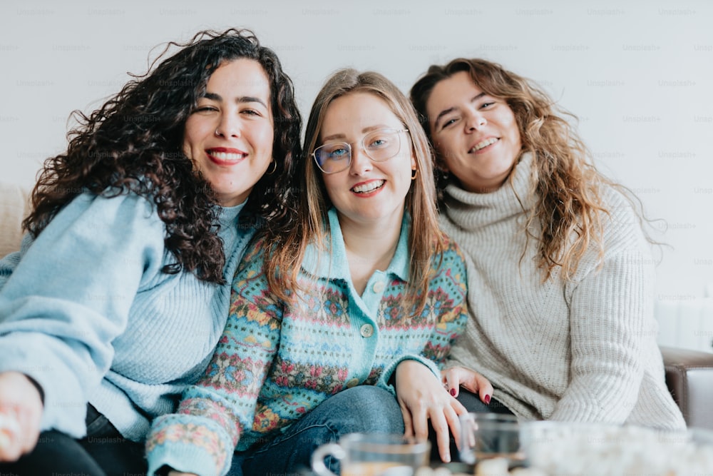 three women sitting on a couch smiling for the camera