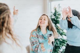 Eine Frau steht vor einem Weihnachtsbaum und hält ein Mikrofon in der Hand