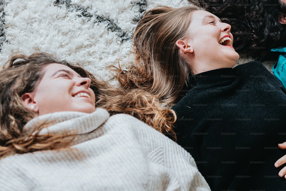 a couple of women laying on top of a rug
