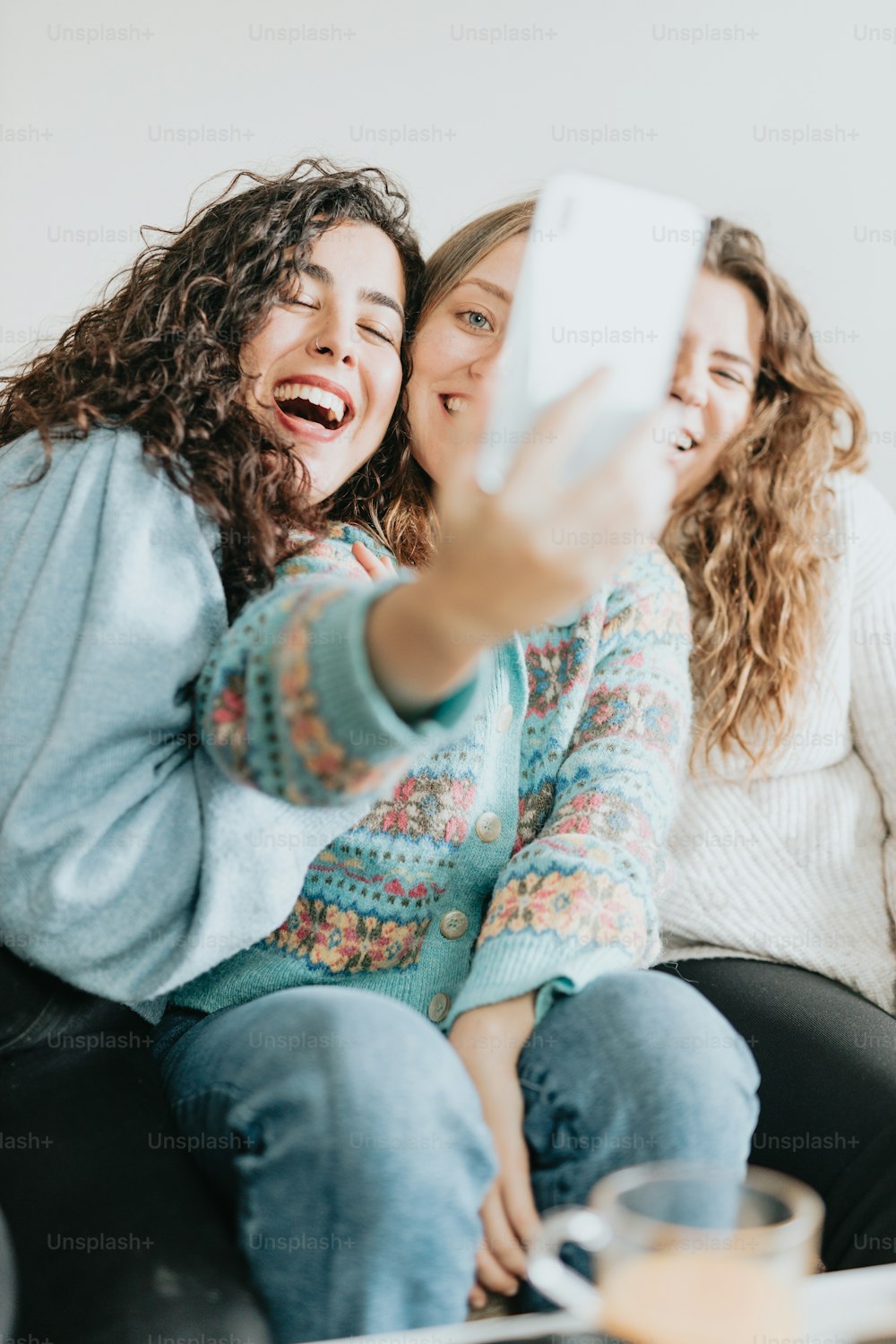 two women sitting on a couch taking a selfie