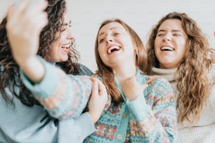 three women laughing and laughing together on a bed