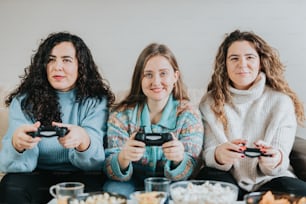 três mulheres sentadas em um sofá jogando videogames