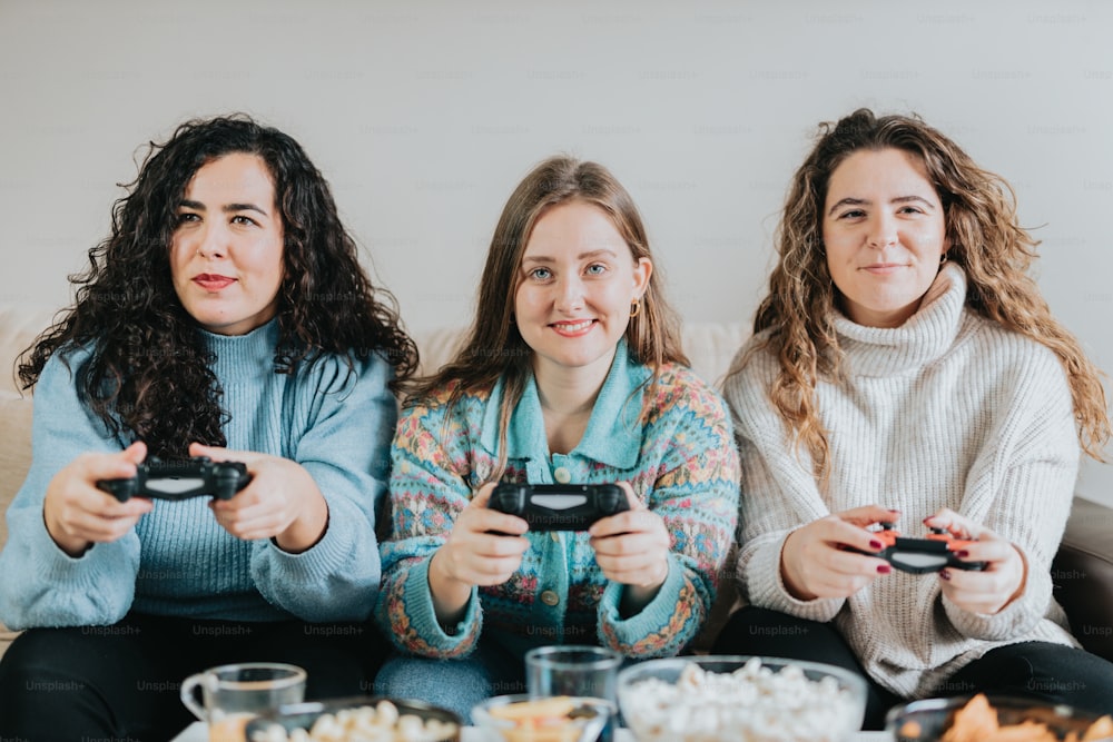 three women sitting on a couch playing video games