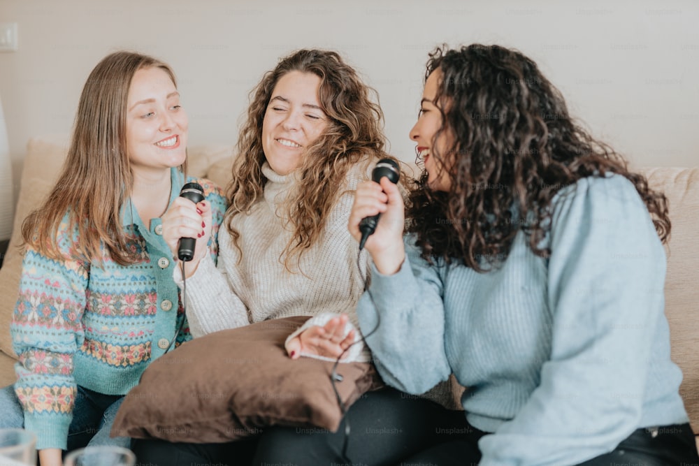 three women sitting on a couch with microphones in their hands