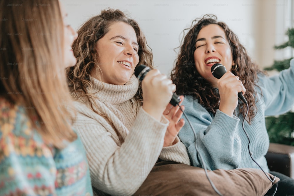 um grupo de mulheres cantando em microfones enquanto sentadas em um sofá