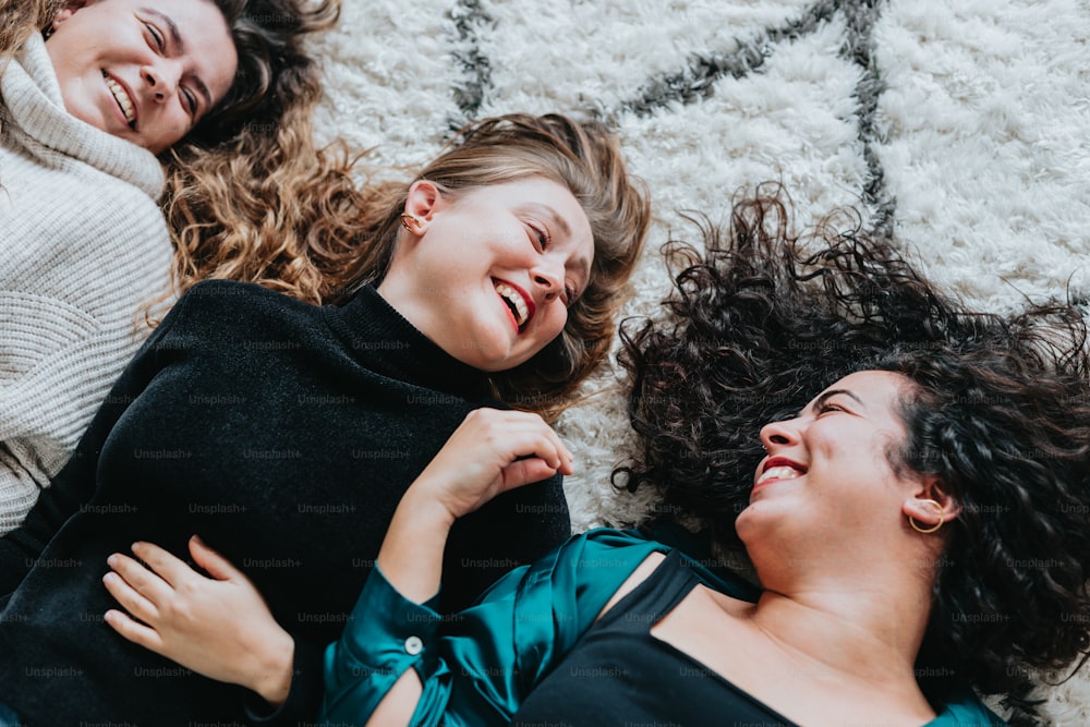 drei Frauen, die auf einem Teppich liegen und lachen und lachen