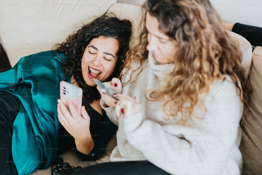 two women laughing while looking at their cell phones
