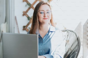 a woman wearing glasses sitting in front of a laptop computer