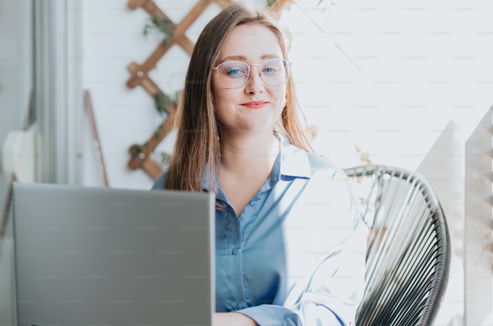 Una donna che porta gli occhiali seduta davanti a un computer portatile