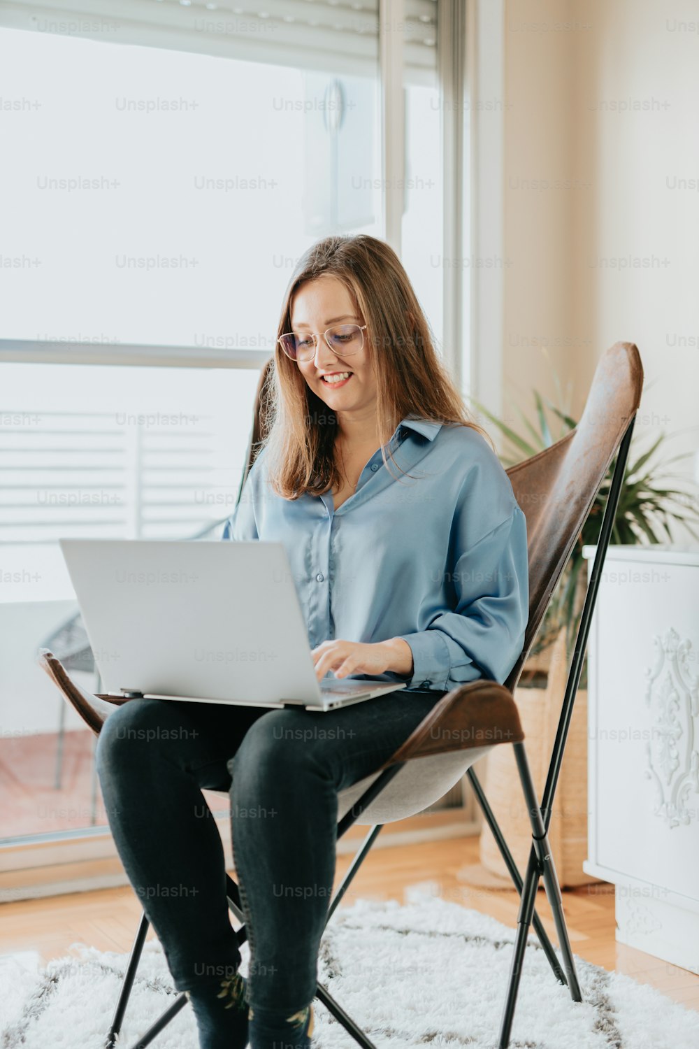 a woman sitting in a chair using a laptop