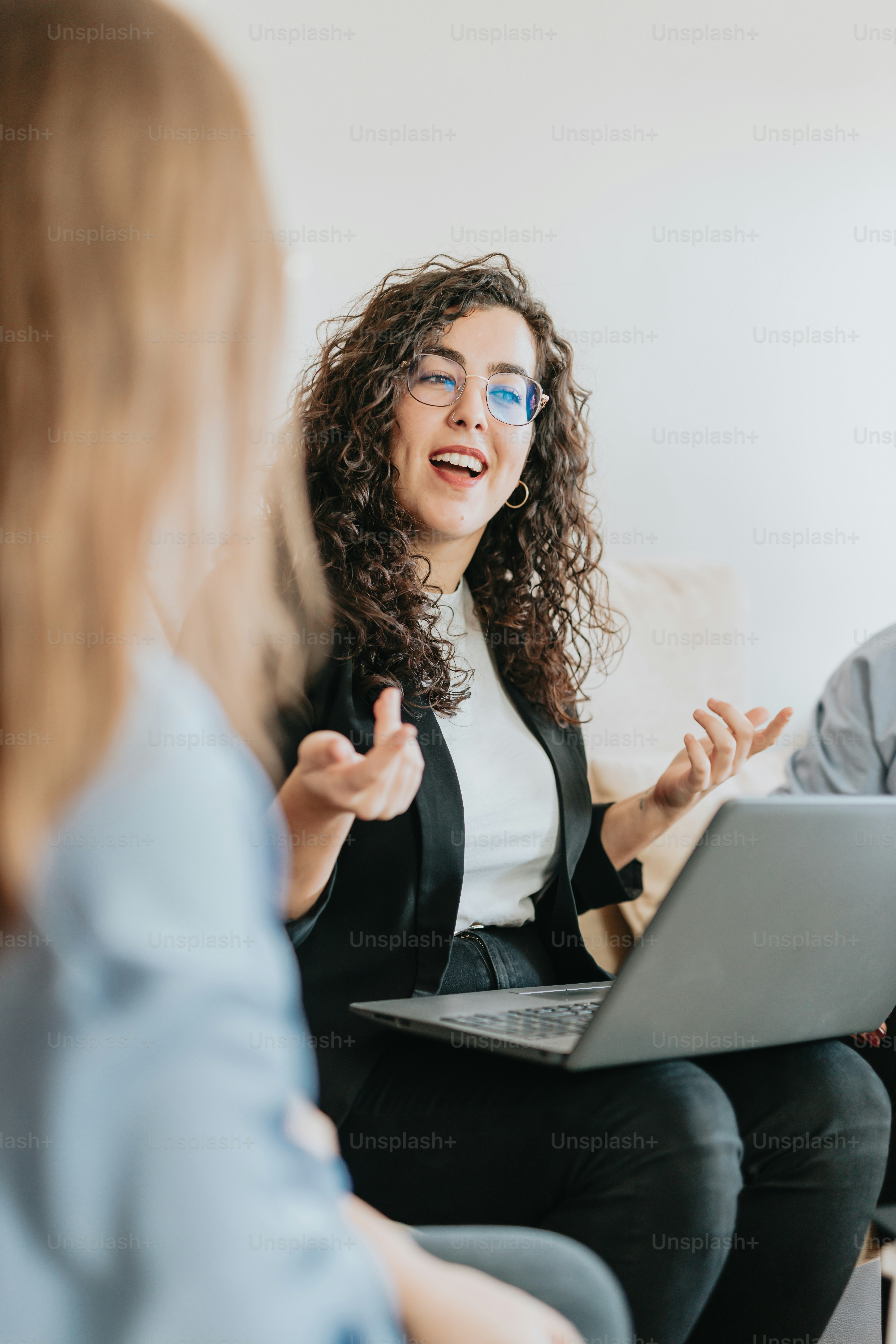 a woman sitting on a couch talking to another woman