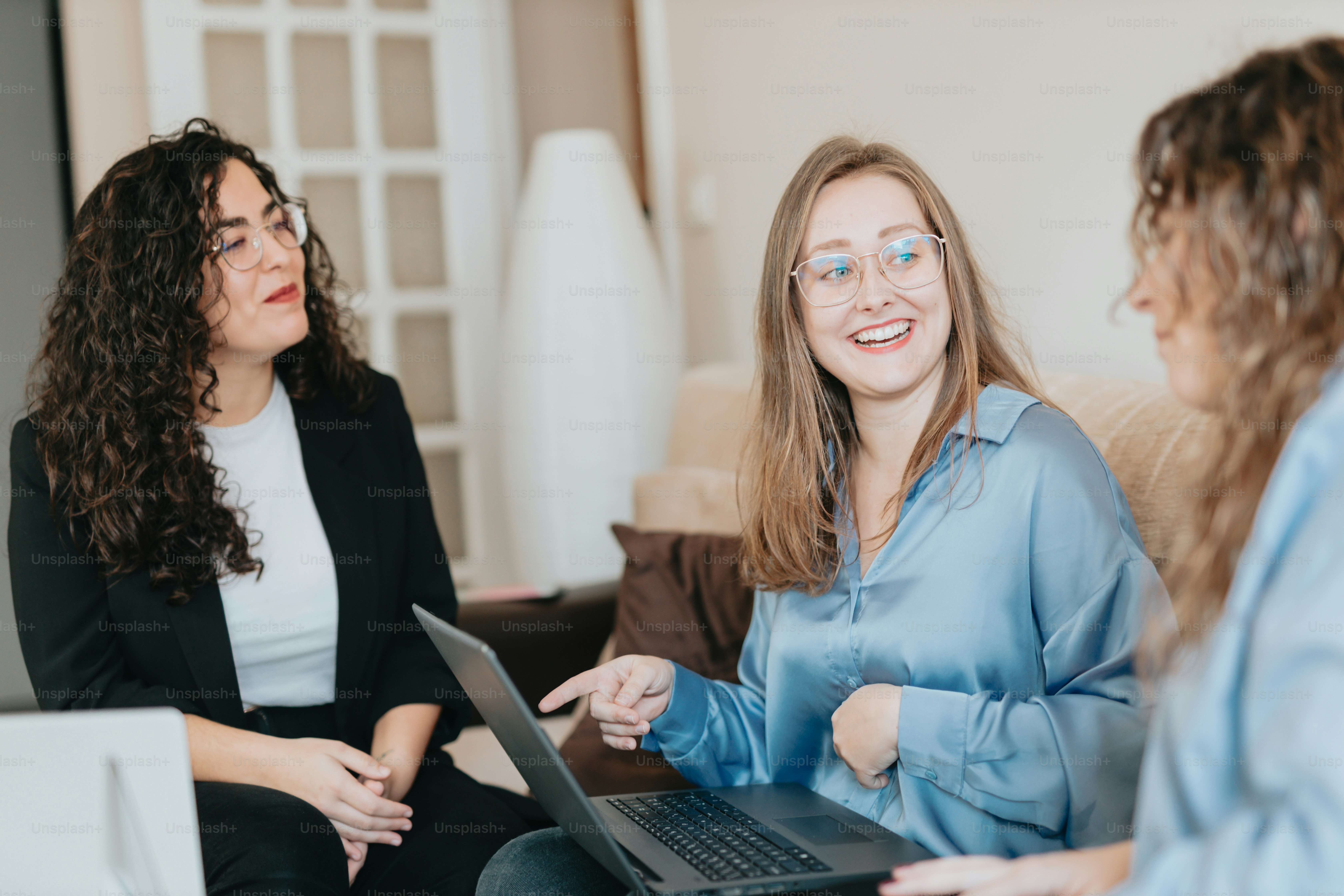 two women sitting on a couch with a laptop
