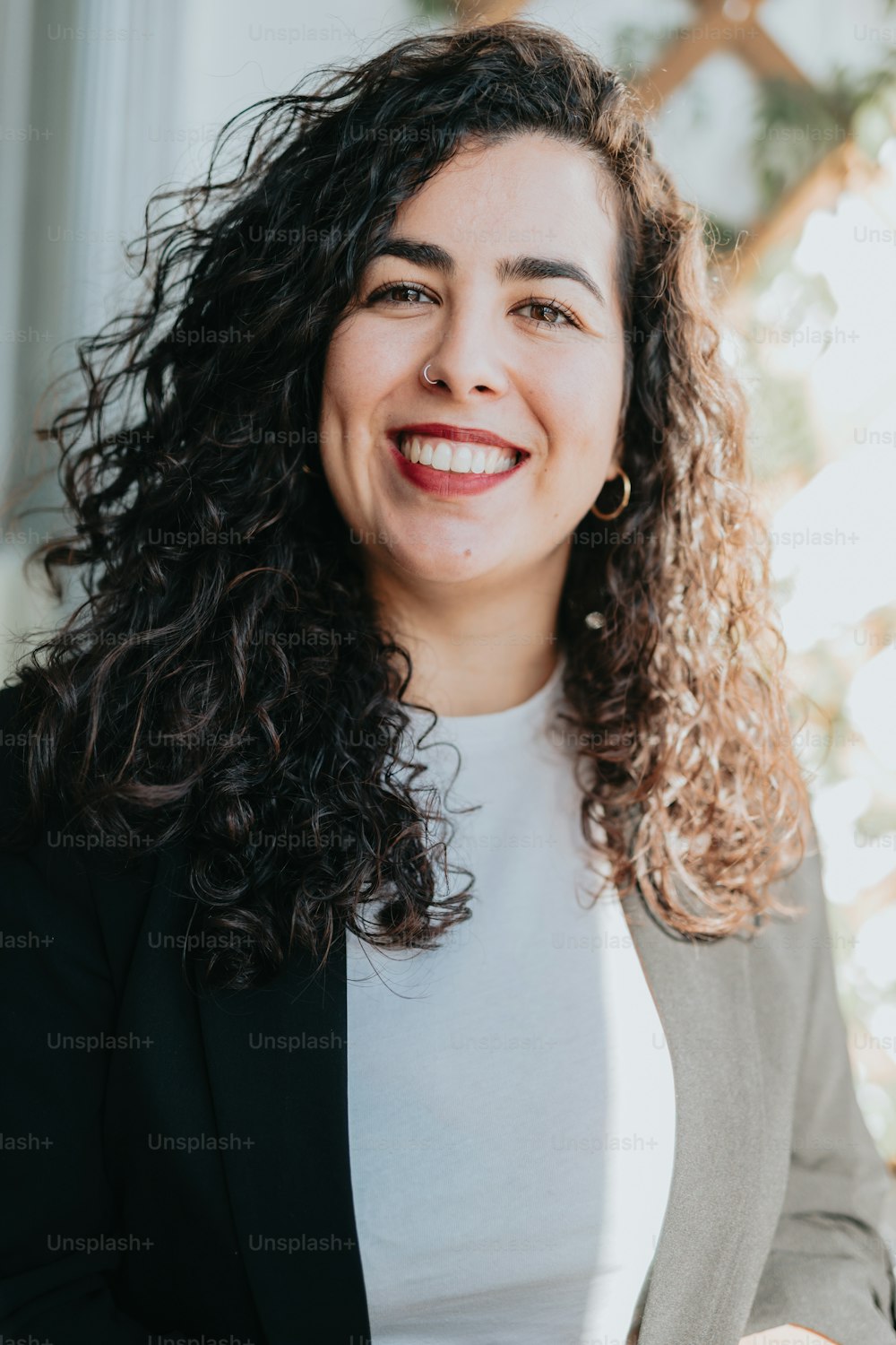 Une femme aux cheveux bouclés souriant à la caméra