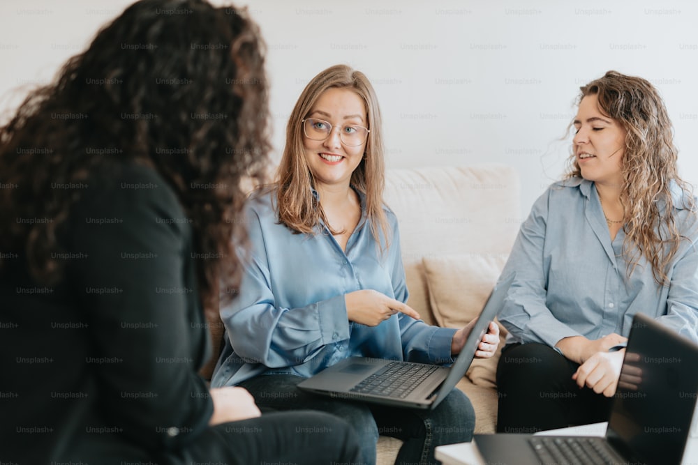 three women sitting on a couch talking to each other