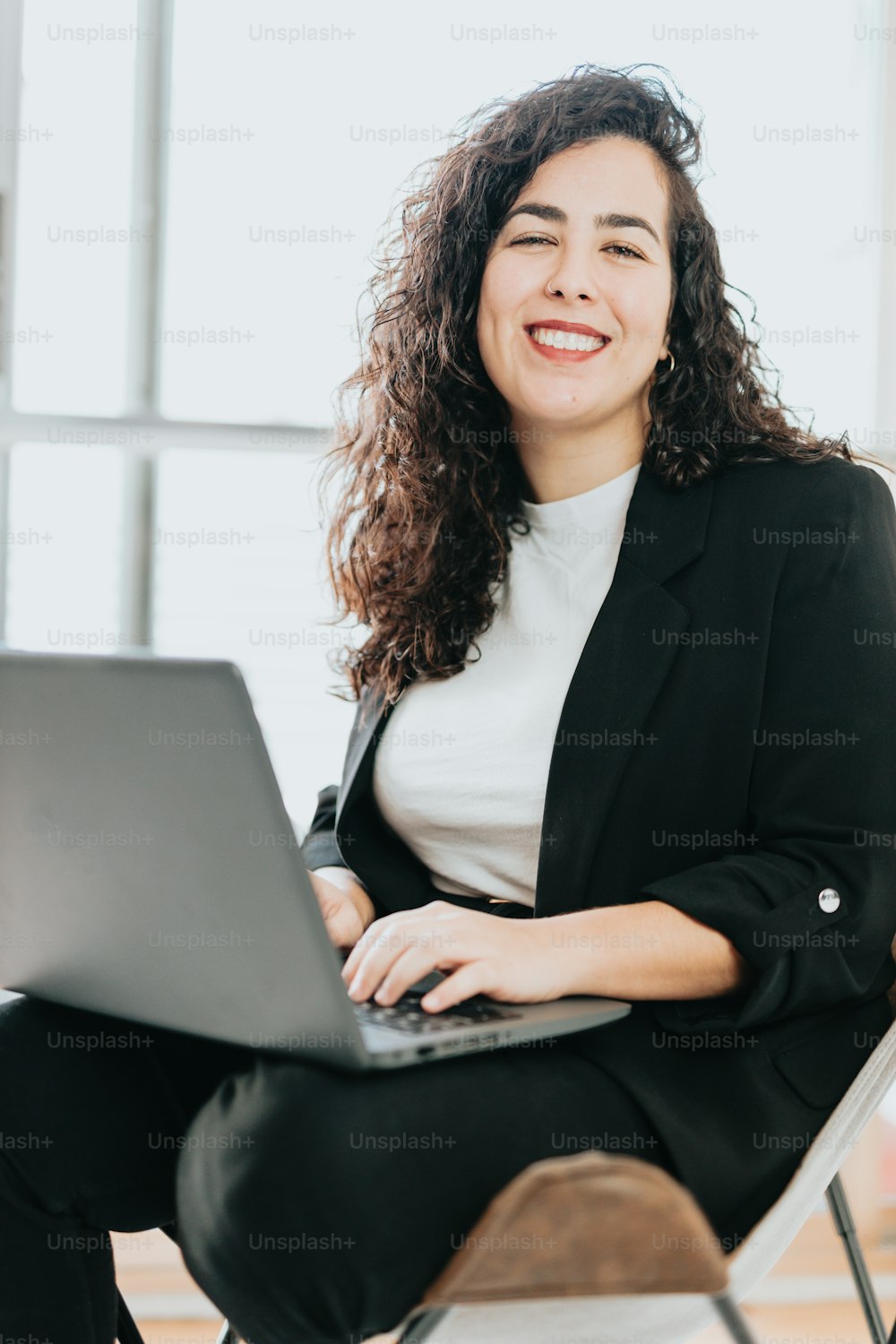 Una donna seduta su una sedia con un computer portatile