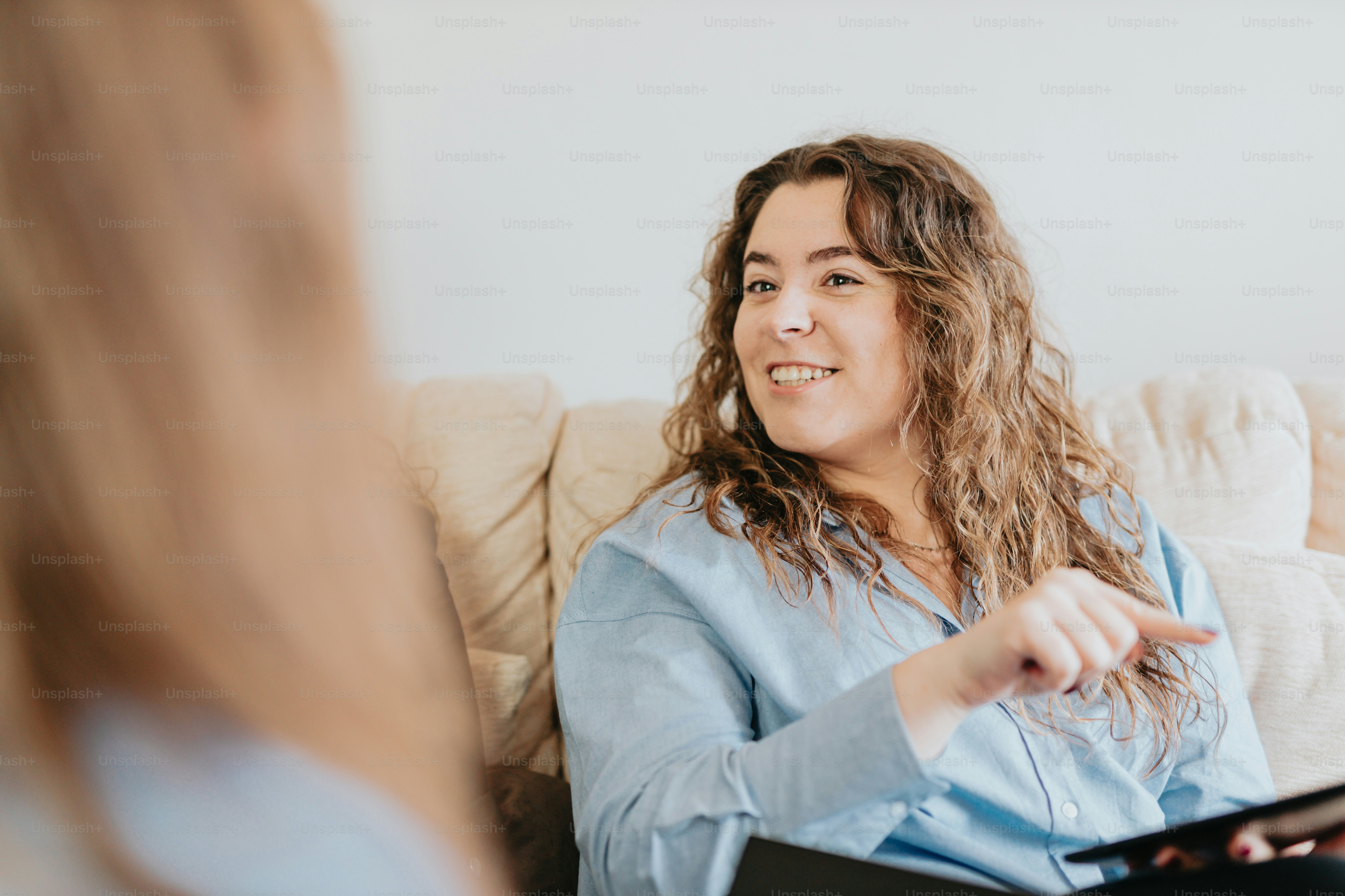 a woman sitting on a couch talking to another woman
