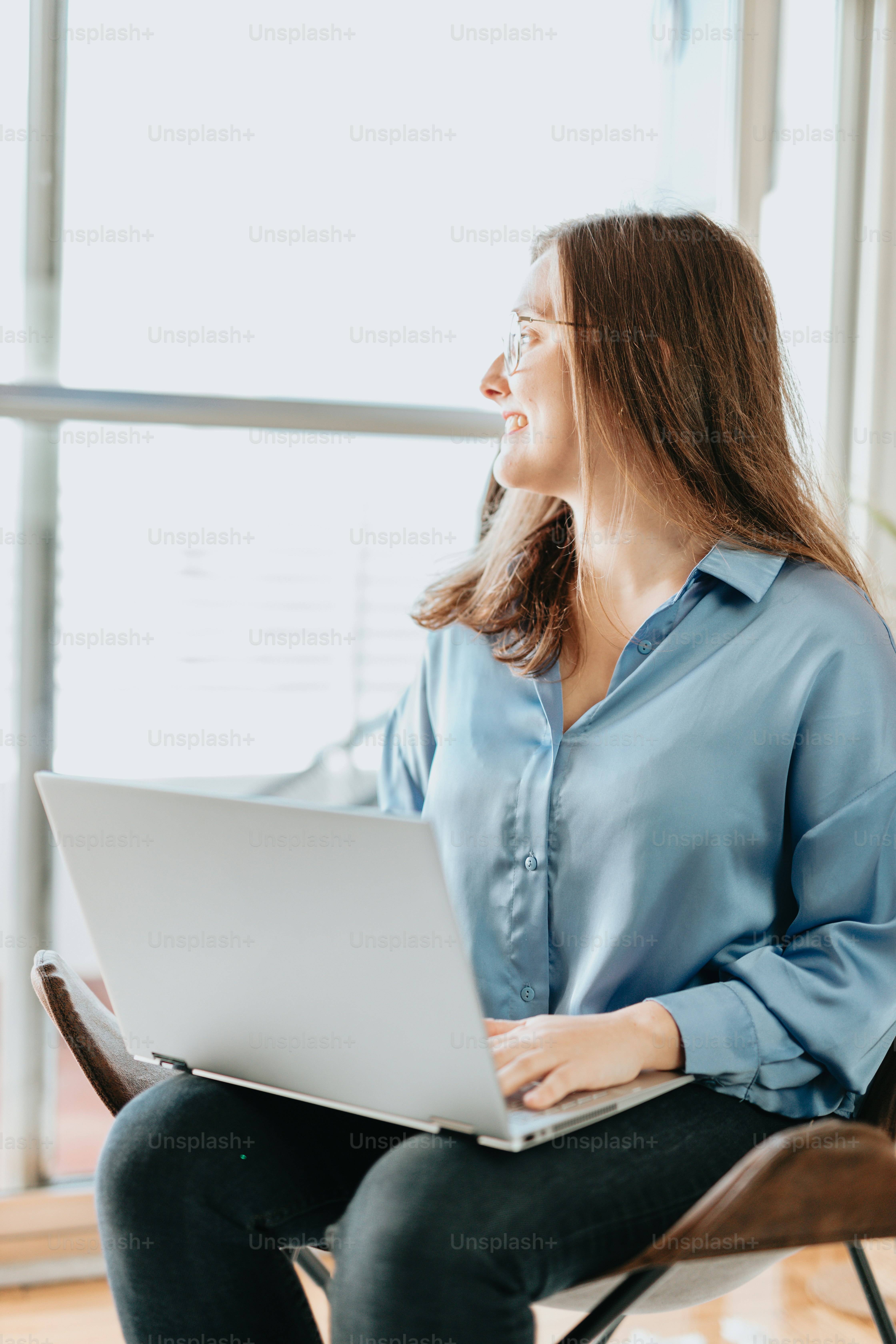 A woman sitting in a chair using a laptop computer photo – Technology ...