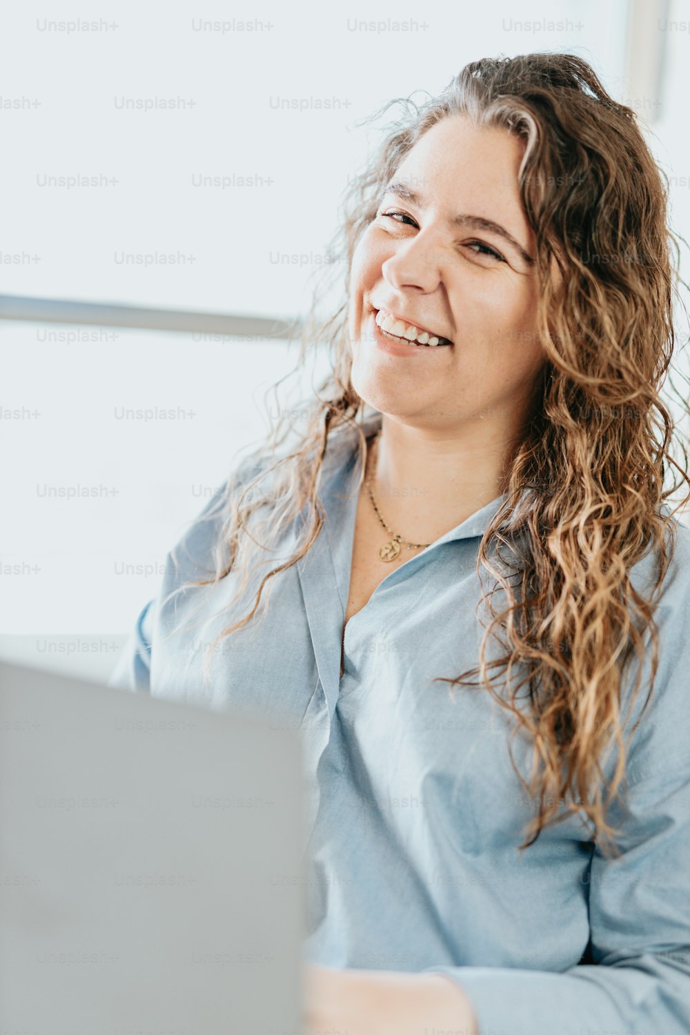 Une femme souriante assise devant un ordinateur portable