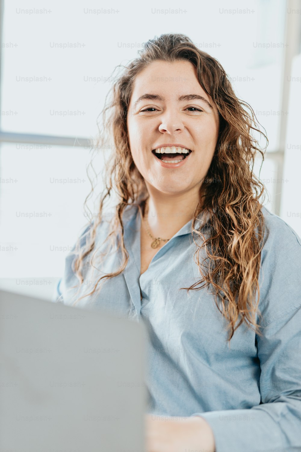 Una mujer sonriente sentada frente a una computadora portátil
